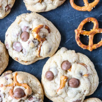 Pretzel cookie with chocolate chips on a dark countertop.