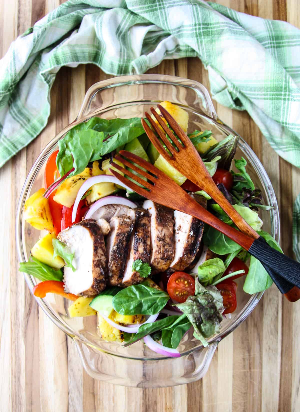 Jerk Chicken Salad in a glass bowl with two wooden salad forks.