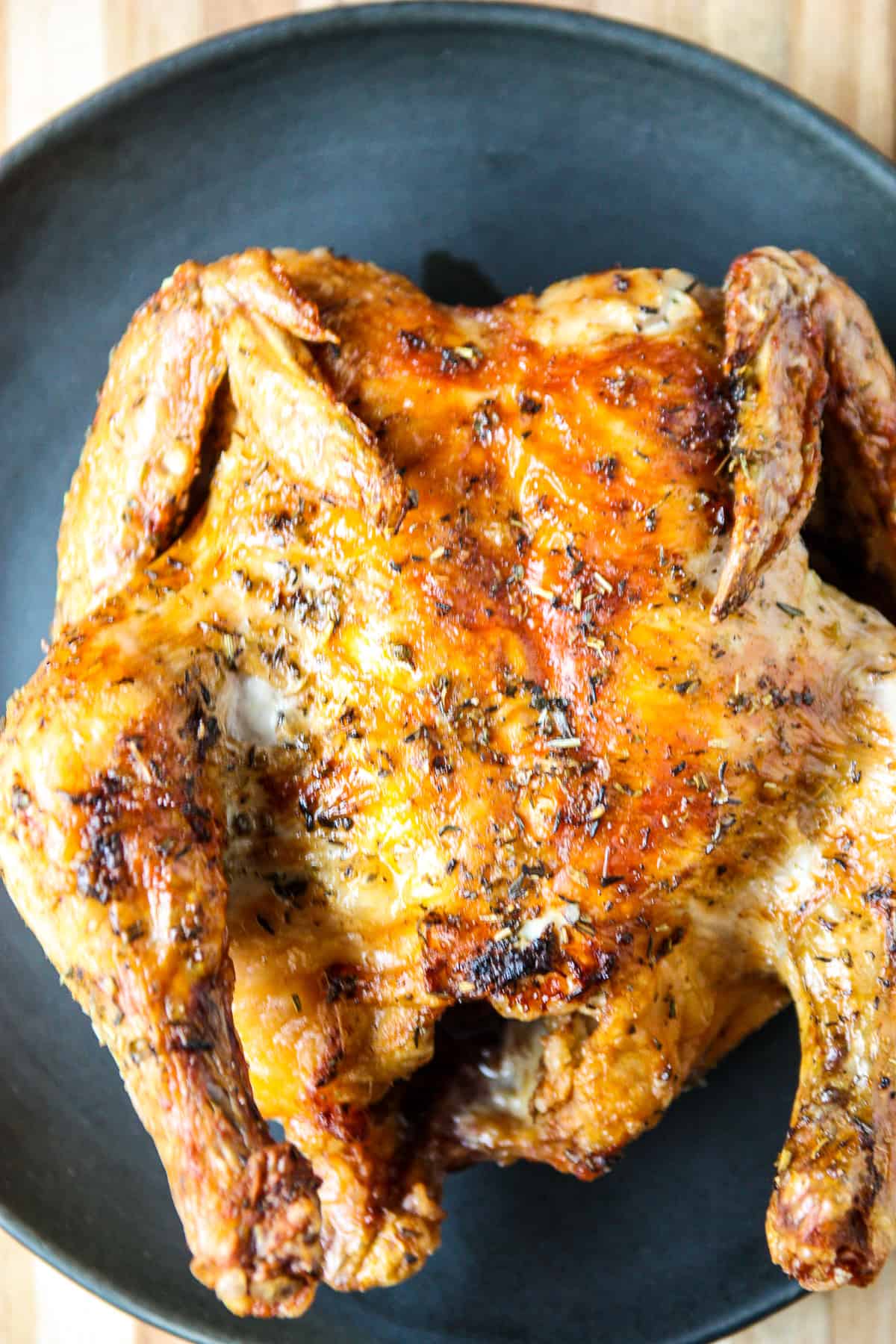 A whole air fryer Cornish hen on a black plate.