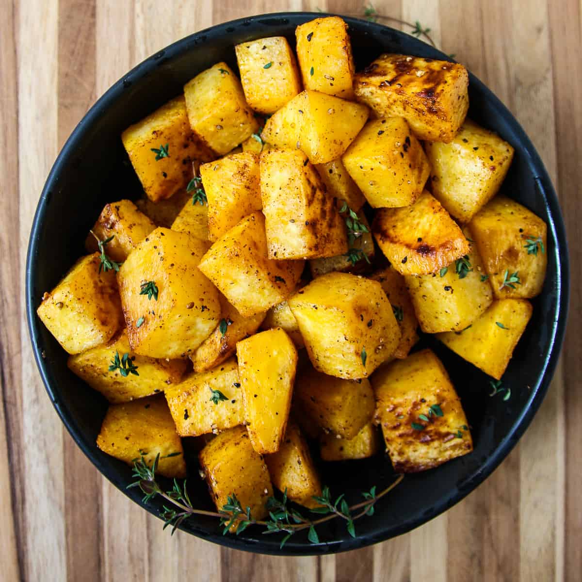 Roasted rutabaga cubes in a black bowl.